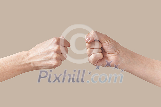 Two hands of man and woman in fist are about to bump symbol of friendship or aggression isolated on beige background. Brotherhood awesome fists bump as agreement. Two hands of man and woman in fist are about to bump symbol of friendship or aggression isolated on beige background. Brotherhood awesome fists bump as agreement.