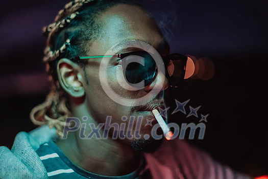Afro Americans smoking a cigar, in the background city lights. High quality photo Afro Americans smoking a cigar, in the background city lights. High quality photo