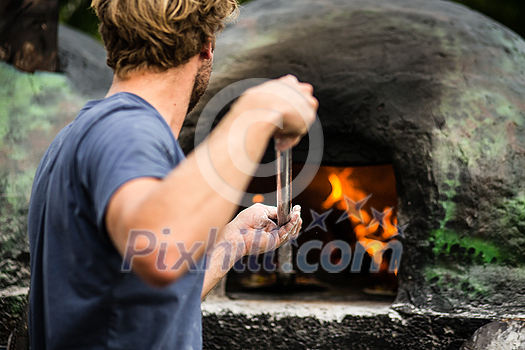 Cook baking pizza in a traditional stone wood fired oven