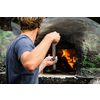 Cook baking pizza in a traditional stone wood fired oven