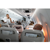 Pretty, young happy woman aboard an airplane during a lang haul commercial flight - stretching her legs a bit, walking in the aisle