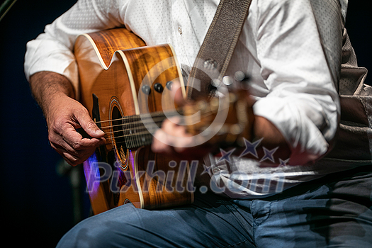 Man playing a guitar on stage (shallow DOF; color toned image)