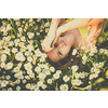 Portrait of young  woman with radiant clean skin lying down amid flowers on a lovely meadow on a spring/summer day