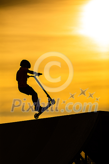 Silhouette of a young boy riding a scooter against the background of a sea sunset Silhouette of a young boy riding a scooter against the background of a sea sunset