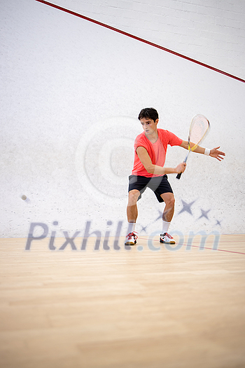 Squash player in action on a squash court (motion blurred image; color toned image)