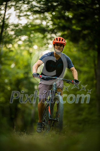 Young man with his mountain bike going for a ride past the city limits in a lovely forest, getting the daily cardio dose Young man with his mountain bike going for a ride past the city limits in a lovely forest, getting the daily cardio dose