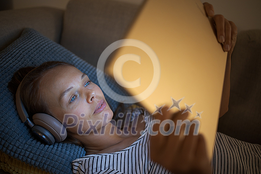 Pretty, young woman using a tablet computer at home in the evening