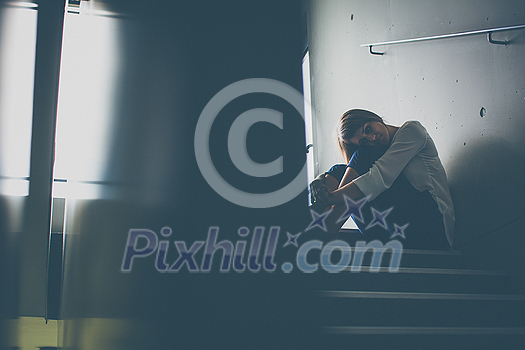 Depressed young woman sitting in a staircase, jobloss due to coronavirus pandemic, Covid-19 outbreak. Unemployment, economic crisis, financial distress concept