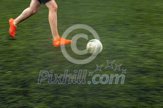 Fast moving feet of a soccer player on a pitch during a match (panned image with motion bliur)