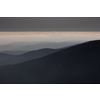 Mountain atmospheric landscape of high mountains in thick fog in rainy weather, panorama of mountain tops in thick clouds, dawn in the mountains in early spring.