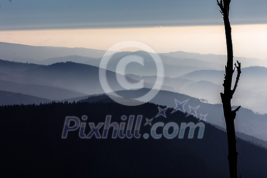 Mountain atmospheric landscape of high mountains in thick fog in rainy weather, panorama of mountain tops in thick clouds, dawn in the mountains in early spring.