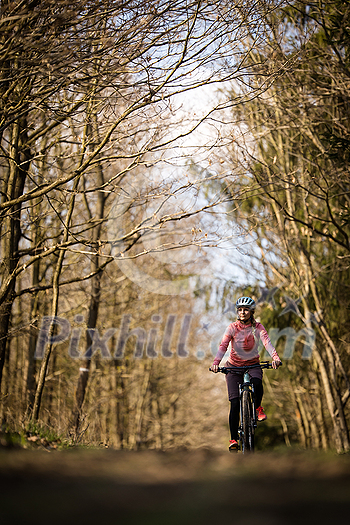 Pretty, young woman with her mountain bike going for a ride past the city limits, getting the daily dose of cardio Pretty, young woman with her mountain bike going for a ride past the city limits, getting the daily dose of cardio