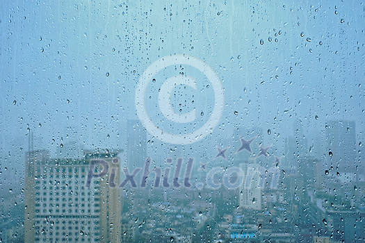 Rain water drops droplets on window glass texture with skyscrapers in background