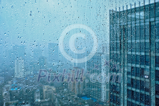 Rain water drops droplets on window glass texture with skyscrapers in background