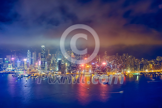 Aerial view of illuminated Hong Kong skyline cityscape downtown skyscrapers over Victoria Harbour in the evening. Hong Kong, China