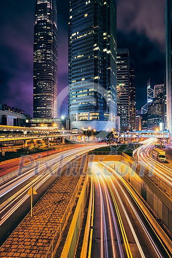 Street traffic in Hong Kong at night. Office skyscraper buildings and busy traffic on highway road with blurred cars light trails. Hong Kong, China