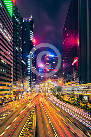 Street traffic in Hong Kong at night. Office skyscraper buildings and busy traffic on highway road with blurred cars light trails. Hong Kong, China