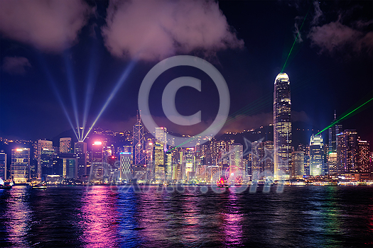 Hong Kong skyline cityscape downtown skyscrapers over Victoria Harbour in the evening illuminated with lasers with tourist boat and ferries . Hong Kong, China