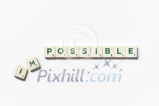 Impossible turning into Possible word made of scrabble blocks with on white background.