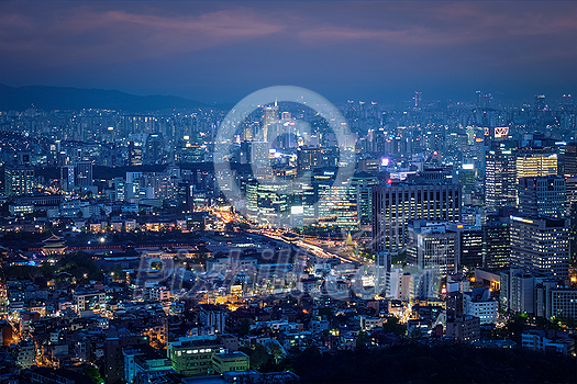 Seoul downtown cityscape illuminated with lights and Gyeongbokgung Palace in the evening view from Inwang mountain. Seoul, South Korea.