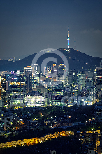 Seoul downtown cityscape illuminated with lights and Namsan Seoul Tower in the evening view from Inwang mountain. Seoul, South Korea.