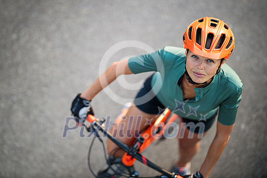 Pretty, young woman with her mountain bike going for a ride past the city limits, getting the daily cardio dose Pretty, young woman with her mountain bike going for a ride past the city limits, getting the daily cardio dose