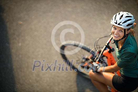 Pretty, young woman with her mountain bike going for a ride past the city limits, getting the daily cardio dose