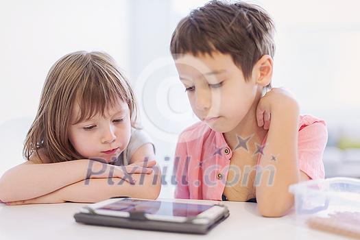 cute little brother and sister having fun at home childrends  playing games on tablet computer