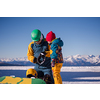 young happy father preparing his little son for the first time on a snowboard during sunny winter day at beautiful  ski resort