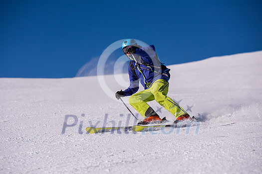 young athlete freestyle Skier having fun while running downhill in beautiful Alpine landscape on sunny day during winter season