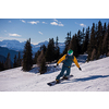 Young freestyle snowboarder running down the slope and ride free style at sunny winter day on Alpine mountains. Winter sport and recreation, leisure outdoor activities.