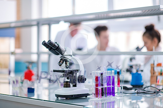 Microscope on the workplace near test tubes with different liquid. Healthcare and biotechnology concept Microscope on the workplace near test tubes with different liquid. Healthcare and biotechnology concept