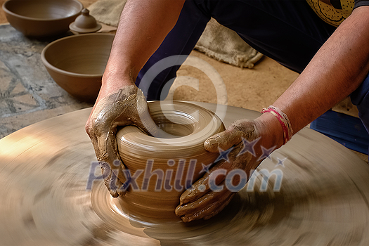 Pottery - skilled wet hands of potter shaping the clay on potter wheel. Pot, vase throwing. Manufacturing traditional handicraft Indian bowl, jar, pot, jug. Shilpagram, Udaipur, Rajasthan, India Pottery - skilled wet hands of potter shaping the clay on potter wheel. Pot, vase throwing. Manufacturing traditional handicraft Indian bowl, jar, pot, jug. Shilpagram, Udaipur, Rajasthan, India