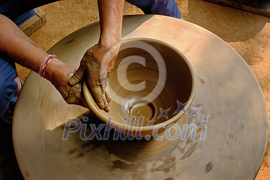 Pottery - skilled wet hands of potter shaping the clay on potter wheel. Pot, vase throwing. Manufacturing traditional handicraft Indian bowl, jar, pot, jug. Shilpagram, Udaipur, Rajasthan, India