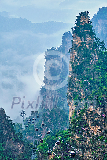 Famous tourist attraction of China - Zhangjiajie stone pillars cliff mountains in fog clouds with cable railway car lift at Wulingyuan, Hunan, China. With camera pan Famous tourist attraction of China - Zhangjiajie stone pillars cliff mountains in fog clouds with cable railway car lift at Wulingyuan, Hunan, China. With camera pan