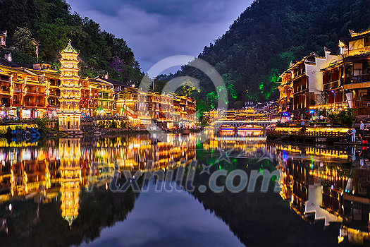 Chinese tourist attraction destination - Feng Huang Ancient Town (Phoenix Ancient Town) on Tuo Jiang River illuminated at night. Hunan Province, China