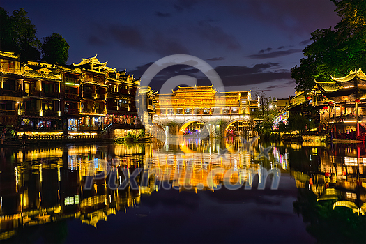 Chinese tourist attraction destination - Feng Huang Ancient Town (Phoenix Ancient Town) on Tuo Jiang River illuminated at night. Hunan Province, China