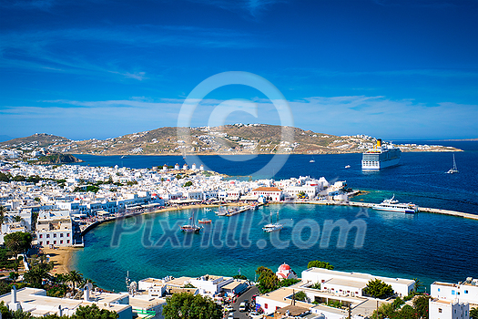 View of Mykonos town Greek tourist holiday vacation destination with famous windmills, and port with boats and yachts. Mykonos, Cyclades islands, Greece