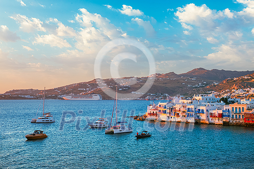 Sunset in Mykonos island, Greece with yachts in the harbor and colorful waterfront houses of Little Venice romantic spot on sunset with cruise ship and yacht boats. Mykonos townd, Greece