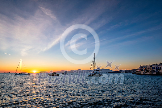 Sunset in Mykonos island, Greece with yachts in the harbor and colorful waterfront houses of Little Venice romantic spot on sunset and cruise ship. Mykonos townd, Greece