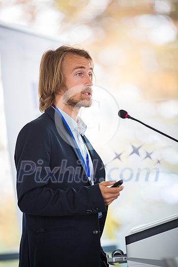 Handsome young man giving a speech at a conference