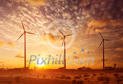 Green renewable energy concept - wind generator turbines sihouettes on sunset. With lens flare and light leak Green renewable energy concept - wind generator turbines sihouettes on sunset. With lens flare and light leak