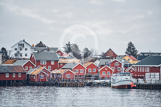 Reine fishing village on Lofoten islands with red rorbu houses in winter with snow with fishing boats. Norway Reine fishing village on Lofoten islands with red rorbu houses in winter with snow with fishing boats. Norway