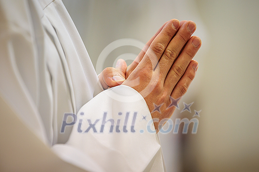 Hands of a priest consecrating a host as the body of Christ to distribute it to the communicants in the church Hands of a priest consecrating a host as the body of Christ to distribute it to the communicants in the church