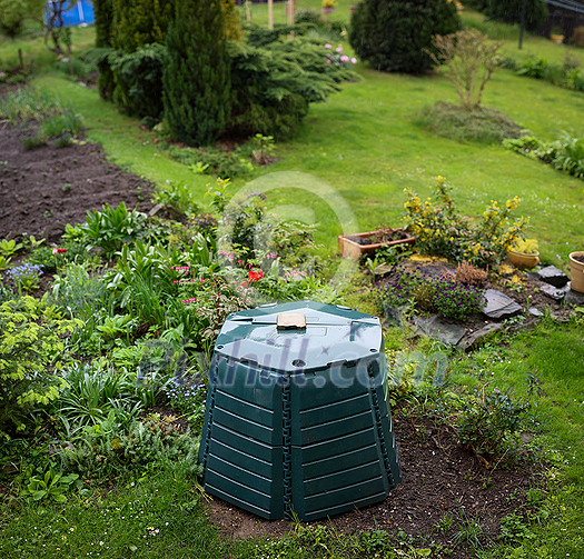 Outdoor composting bin for recycling kitchen and garden organic waste in a lovely lush garden Outdoor composting bin for recycling kitchen and garden organic waste in a lovely lush garden