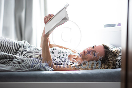 Pretty, middle-aged woman reading a book before sleep in bed Pretty, middle-aged woman reading a book before sleep in bed