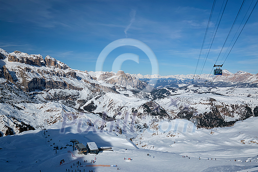 View of a ski resort piste with people skiing in Dolomites in Italy with cable car ski lift. Ski area Arabba. Arabba, Italy View of a ski resort piste with people skiing in Dolomites in Italy with cable car ski lift. Ski area Arabba. Arabba, Italy