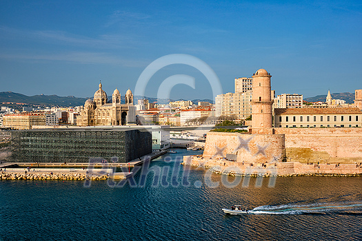 Marseille Old Port and Fort Saint-Jean and Museum of European and Mediterranean Civilisations and Marseille Cathedral on sunset with passing boat. Marseille, France Marseille Old Port and Fort Saint-Jean and Museum of European and Mediterranean Civilisations and Marseille Cathedral on sunset with passing boat. Marseille, France