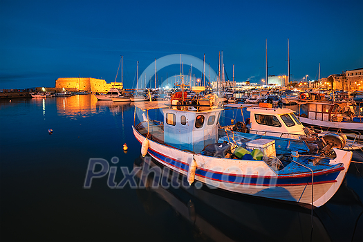 Venetian Fort Venetian fortress of Koules Castello a Mare castle in Heraklion and moored Greek fishing boats in port, Crete Island, Greece in the evening Venetian Fort Venetian fortress of Koules Castello a Mare castle in Heraklion and moored Greek fishing boats in port, Crete Island, Greece in the evening