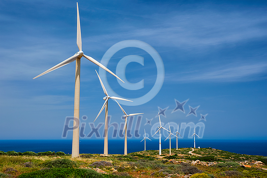 Green renewable alternative energy concept - wind generator turbines generating electricity. Wind farm on Crete island, Greece with road Green renewable alternative energy concept - wind generator turbines generating electricity. Wind farm on Crete island, Greece with road
